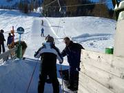 Staff hand the pole to skiers at the button lift