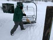 Falling snow is swept from the seats of the chairlifts.