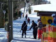 The staff assists with getting on the drag lift.