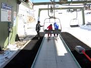 The staff assists with boarding at the chairlift.