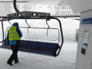 Falling snow is swept from the seats of the chairlifts