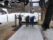 The staff assists with boarding the chairlift.